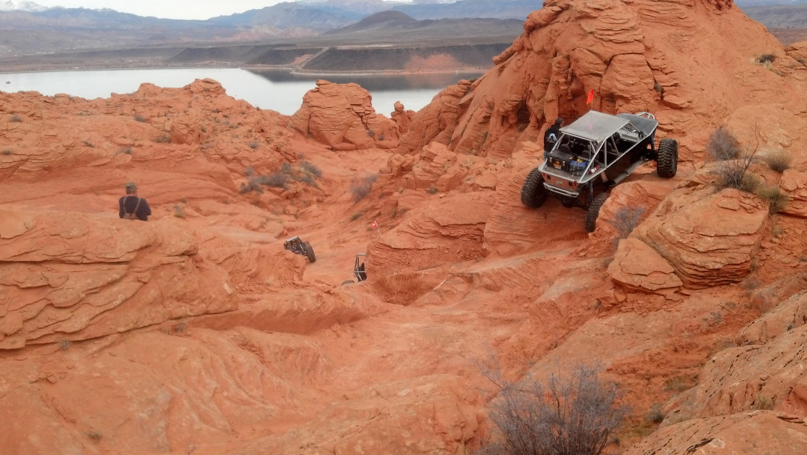 Side-by-sides climbing red slickrock above Sand Hollow Reservoir